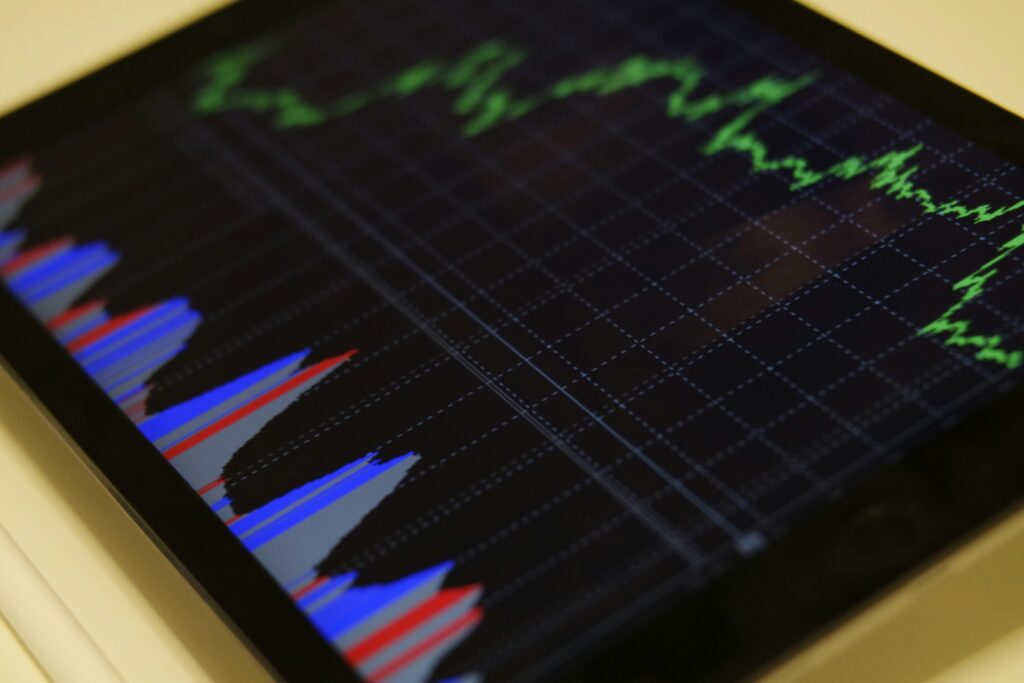 Közeli kép egy táblagép képernyőjéről, amely pénzügyi grafikonokat jelenít meg, hasonlóan ahhoz, hogy a Core Web Vitals hogyan befolyásolja a webhely teljesítményét. A zöld vonaldiagram mutatja a trendeket, míg a piros és kék oszlopdiagramok az összehasonlításokat. A háttér egy sötét rácsmintát tartalmaz, amely egy elegáns WordPress oldal elrendezésre emlékeztet.
